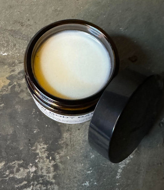 Jar of cream, Ghost Light Farm's Beef Tallow, with a black lid on a textured surface